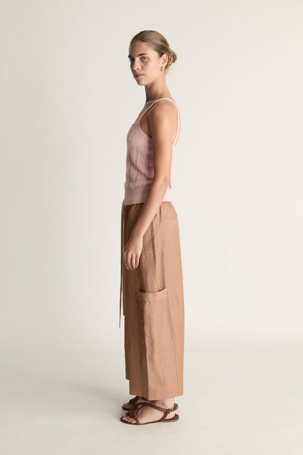 Woman wearing a pink top and brown pants on a white background