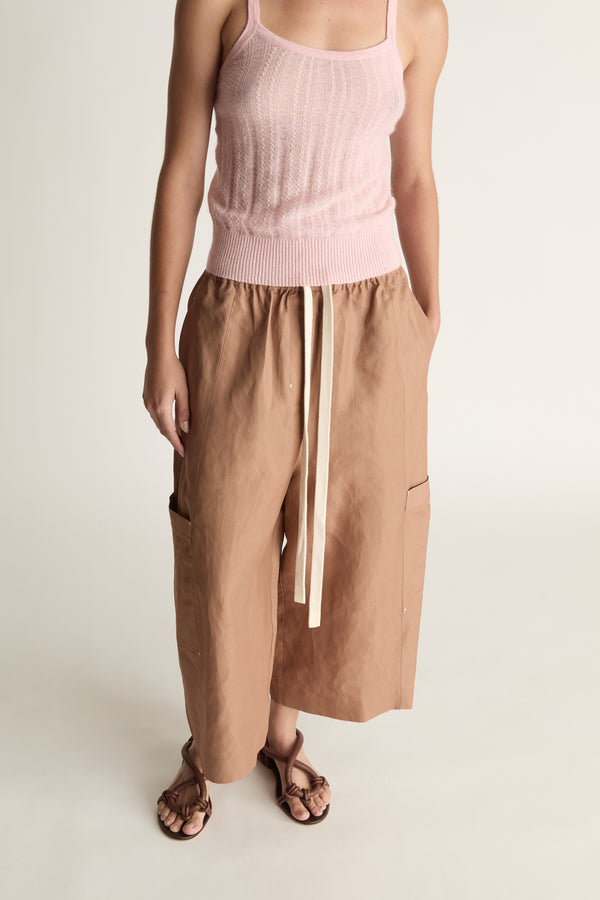 Woman wearing a pink top and brown pants on a white background