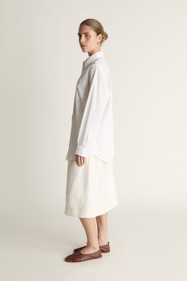 Person wearing a long white shirt and skirt on a plain background