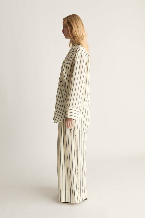 Side view of a woman wearing a pyama style matching yellow and black stripe set on a white background