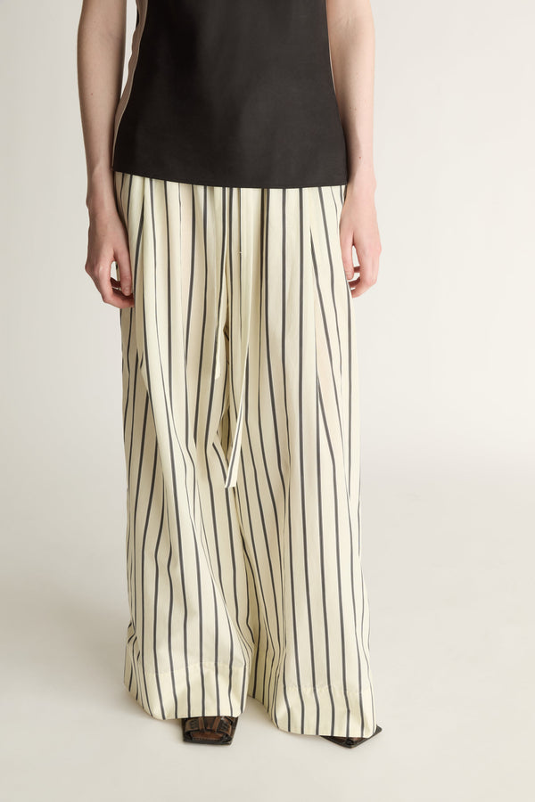 A close-up of a pair of lemon yellow and black striped  drawstring pants on a white background.
