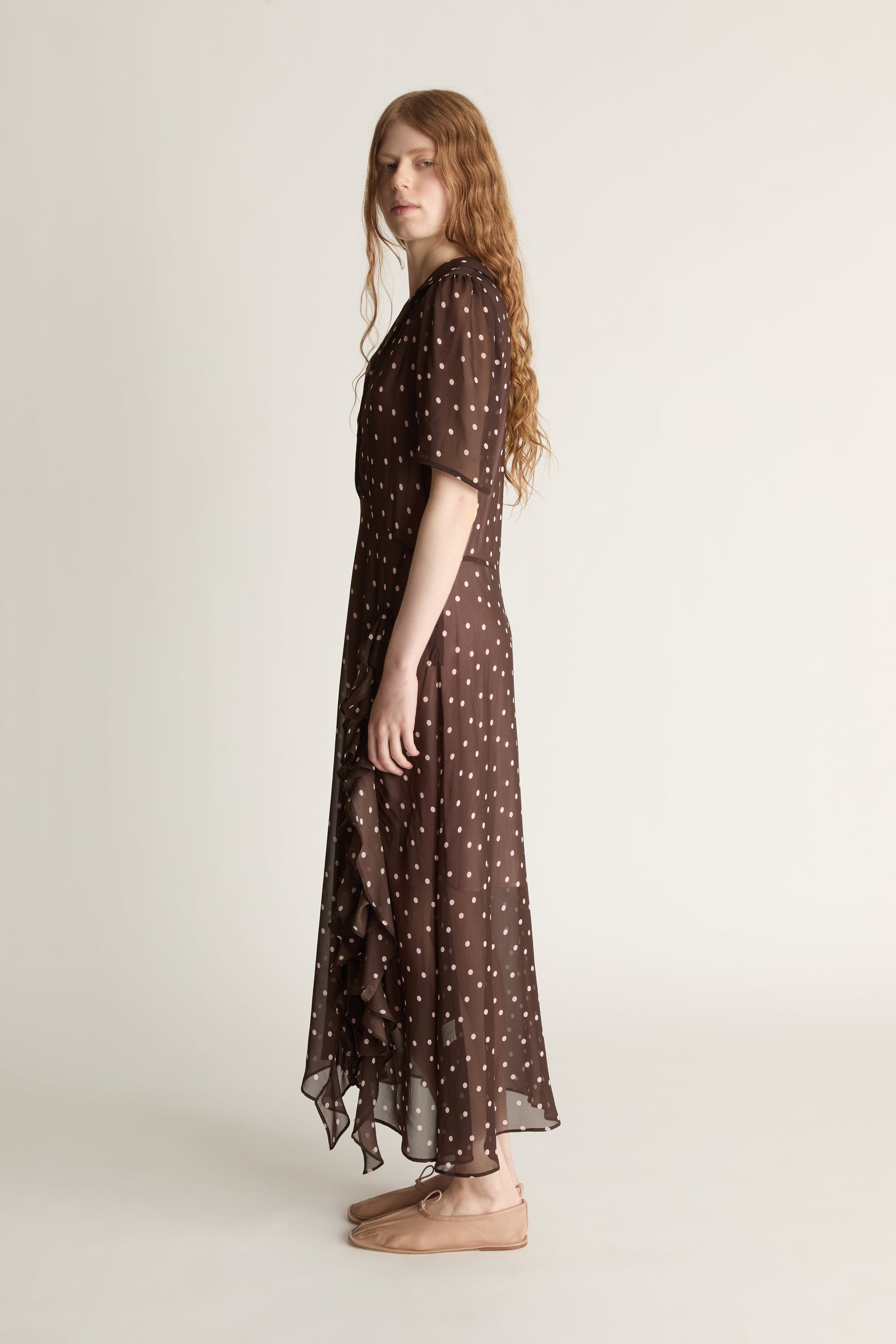 Woman wearing a brown polka dot dress on a white background