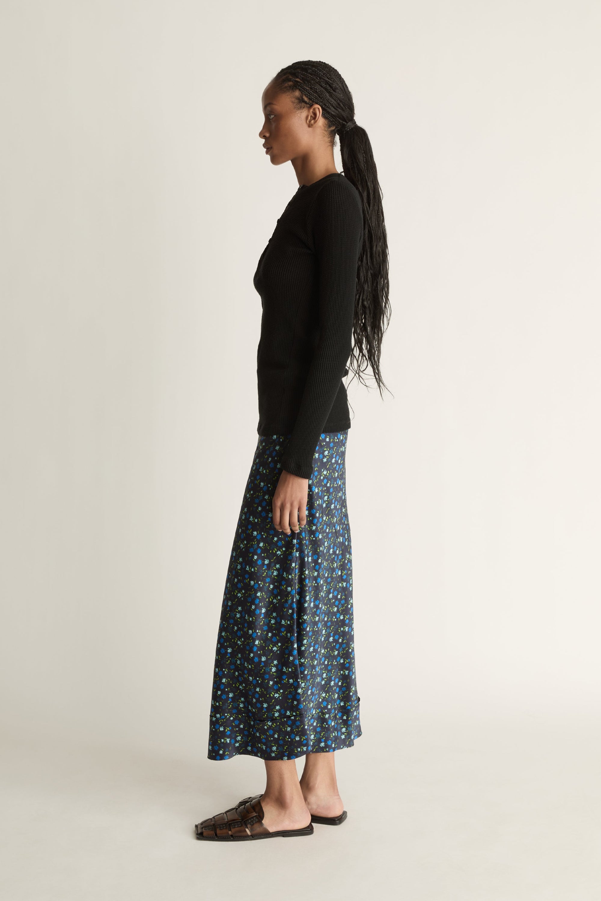 Woman wearing a black long-sleeve top and patterned skirt on a white background