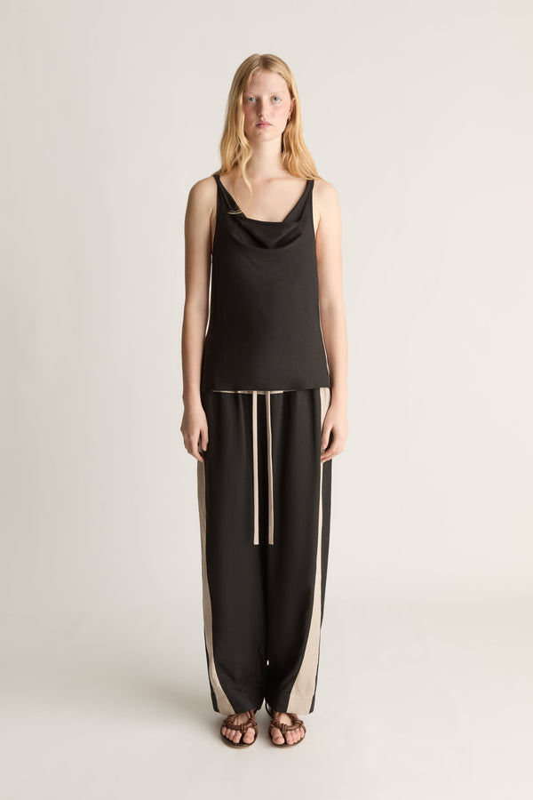 Front view image of a woman wearing a Black bias  tank top and a pair of black drawstring trousers on a white background