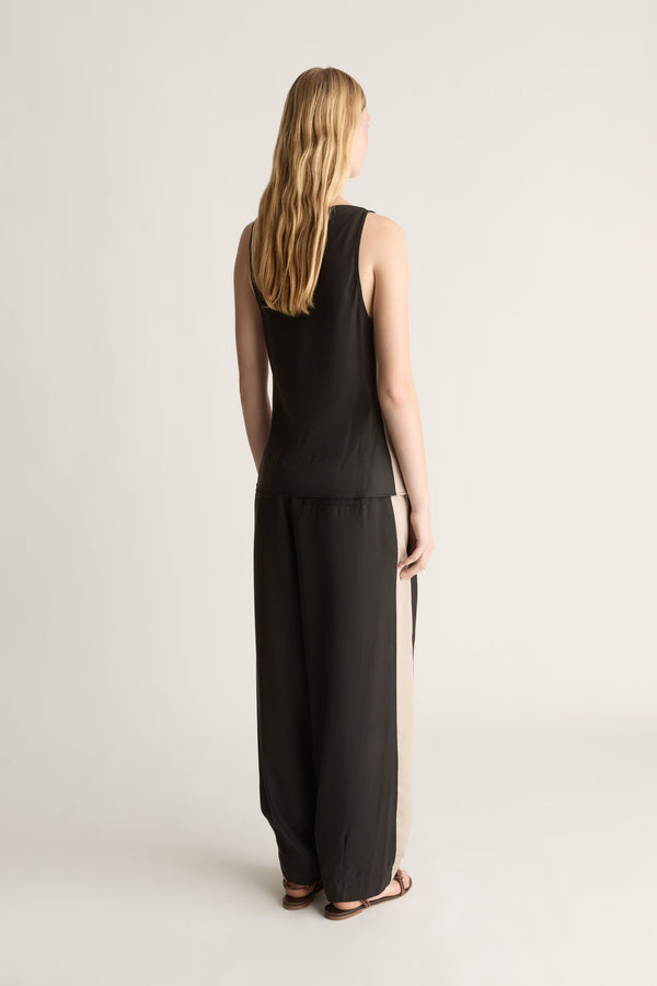 Back view of a woman wearing a black bias tencel blouse and pants on a white background 
