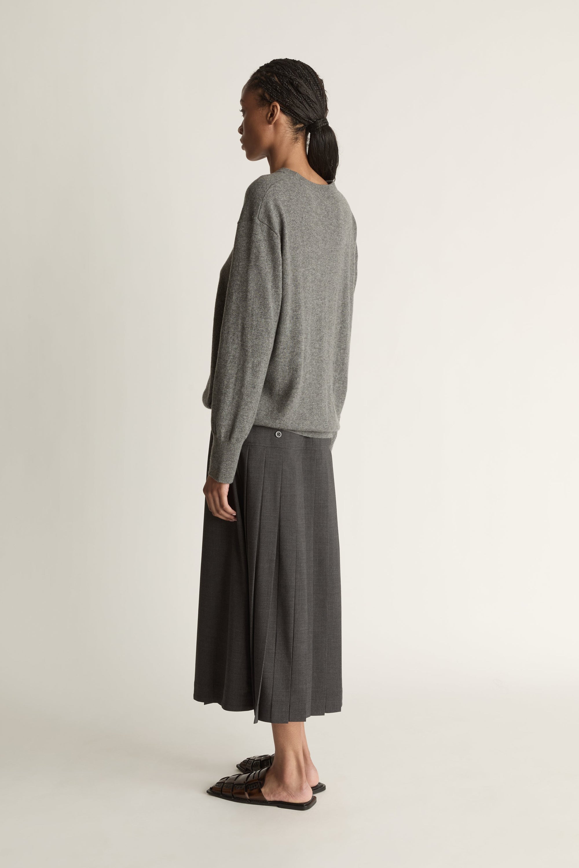 Woman wearing a gray sweater and dark gray skirt on a white background