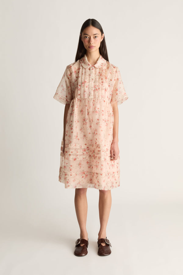 A front view image of a woman wearing a floral mini dress on a white background