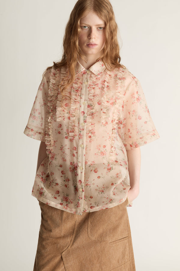 Person wearing a floral blouse and brown skirt on a white background