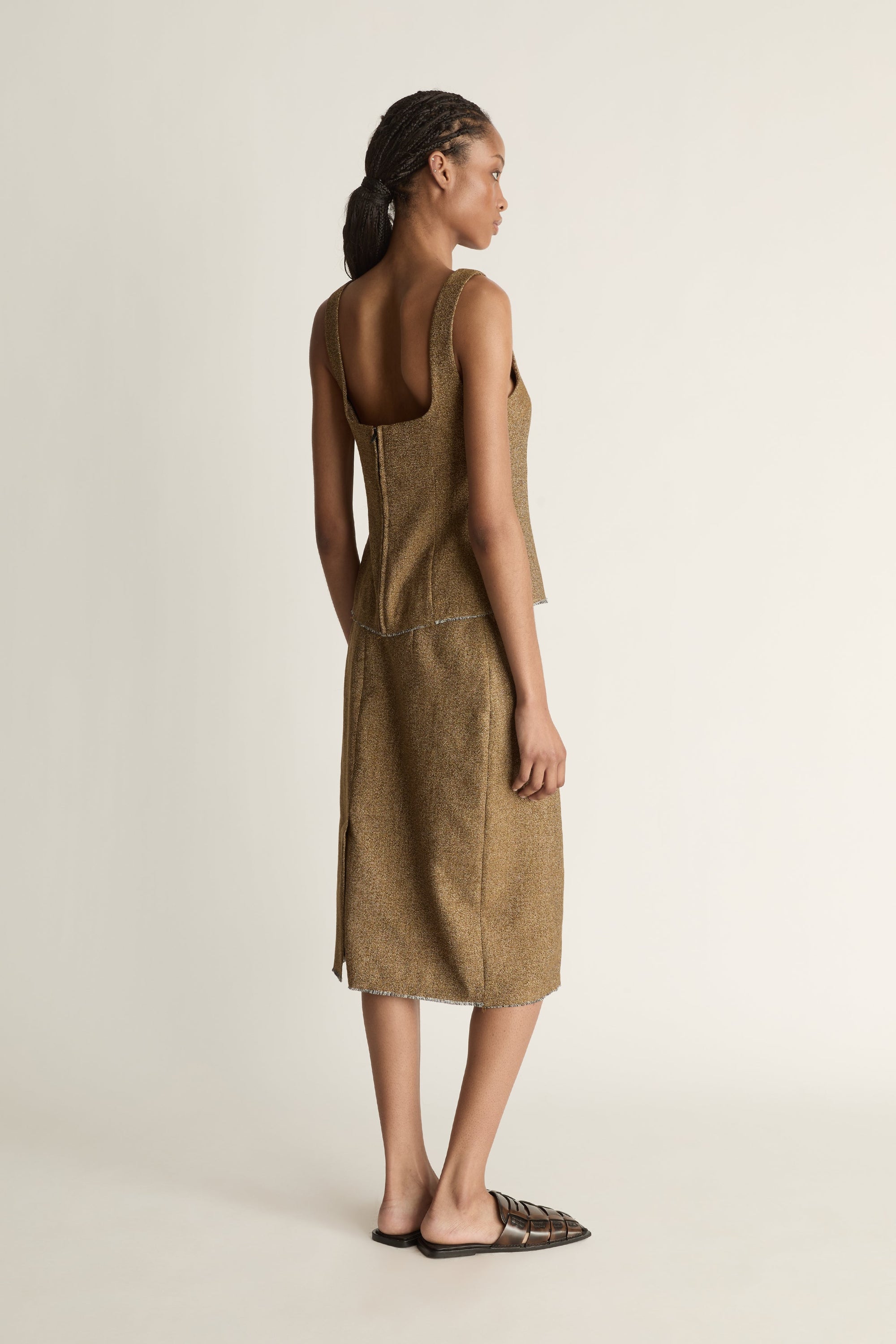 Back view of a woman wearing a brown wool/linen skirt with a back slit