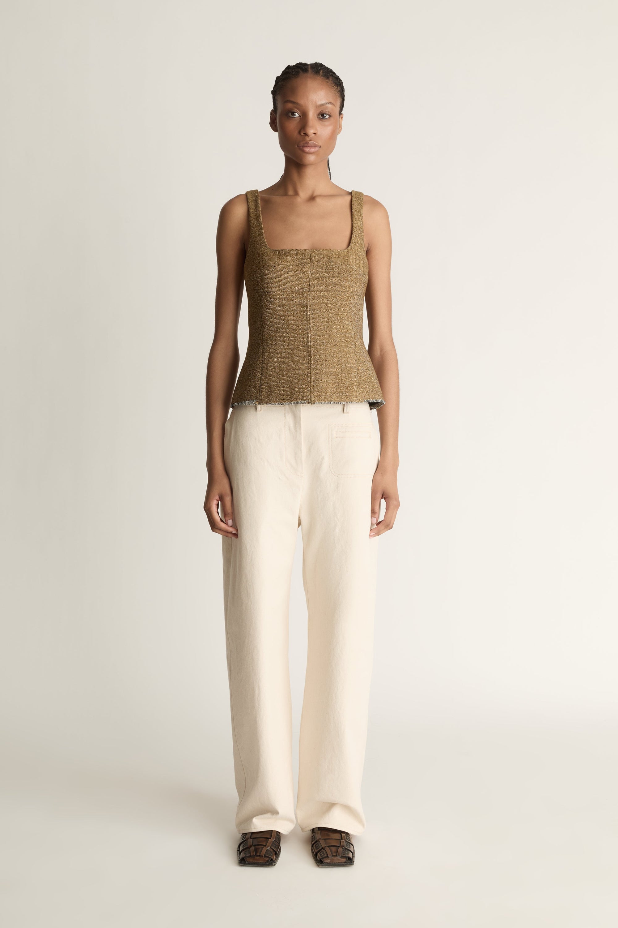 Front view image of a woman wearing a brown wool/linen blend tank top and ivory  straight leg jeans on a white background/ 