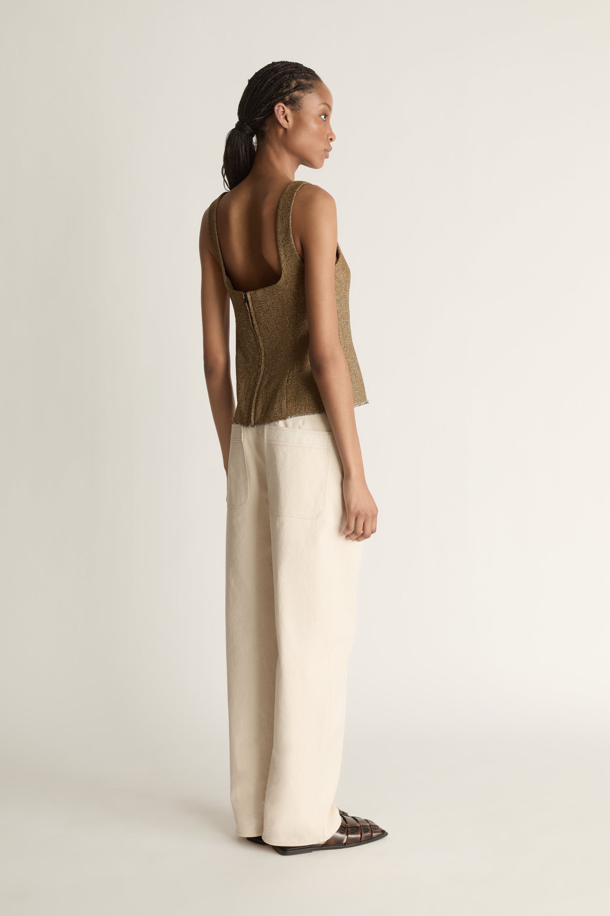 Back view image of a woman wearing the Esme Top with a pair of ivory jeans on a white background