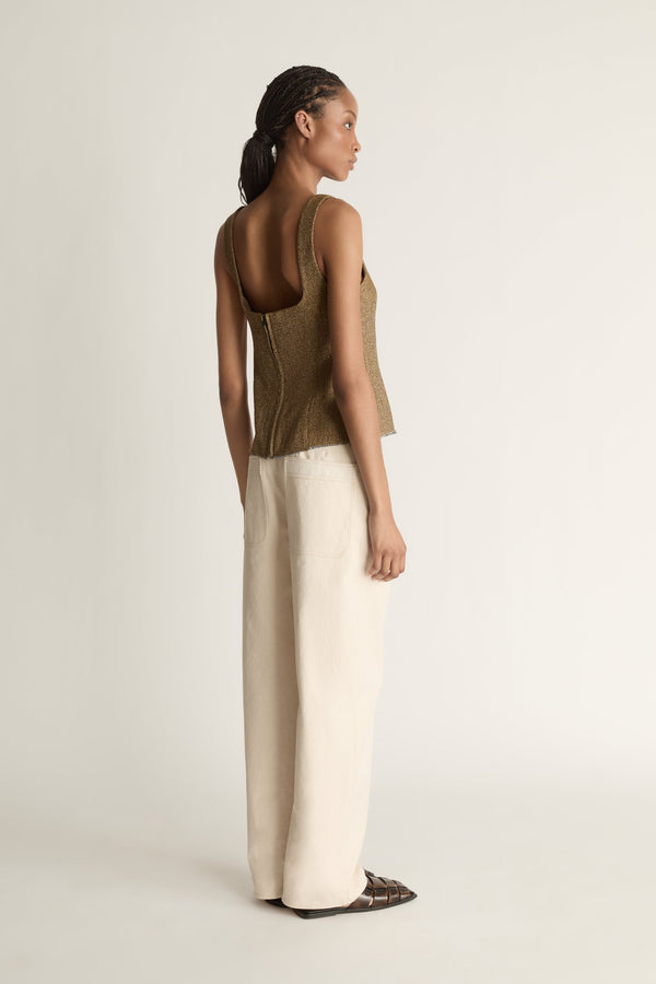 Back view image of a woman wearing the Esme Top with a pair of ivory jeans on a white background