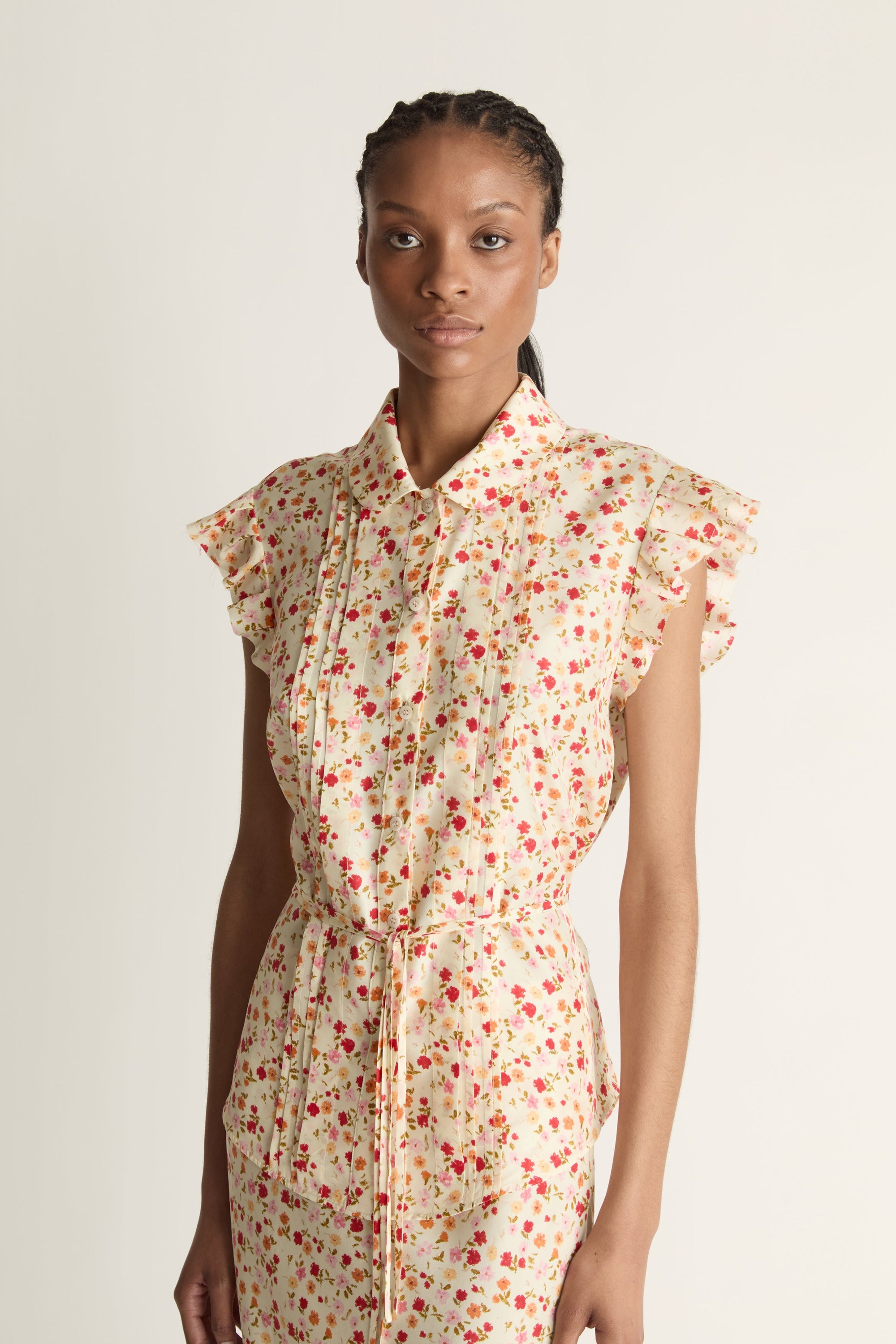 A woman wearing a floral shirt and skirt on a plain background