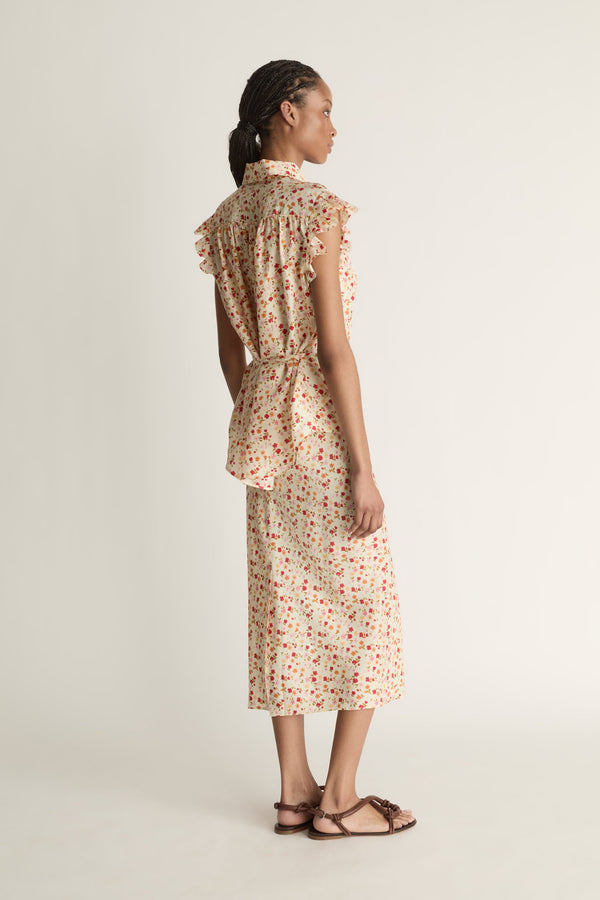 A woman wearing a floral shirt and skirt on a plain background