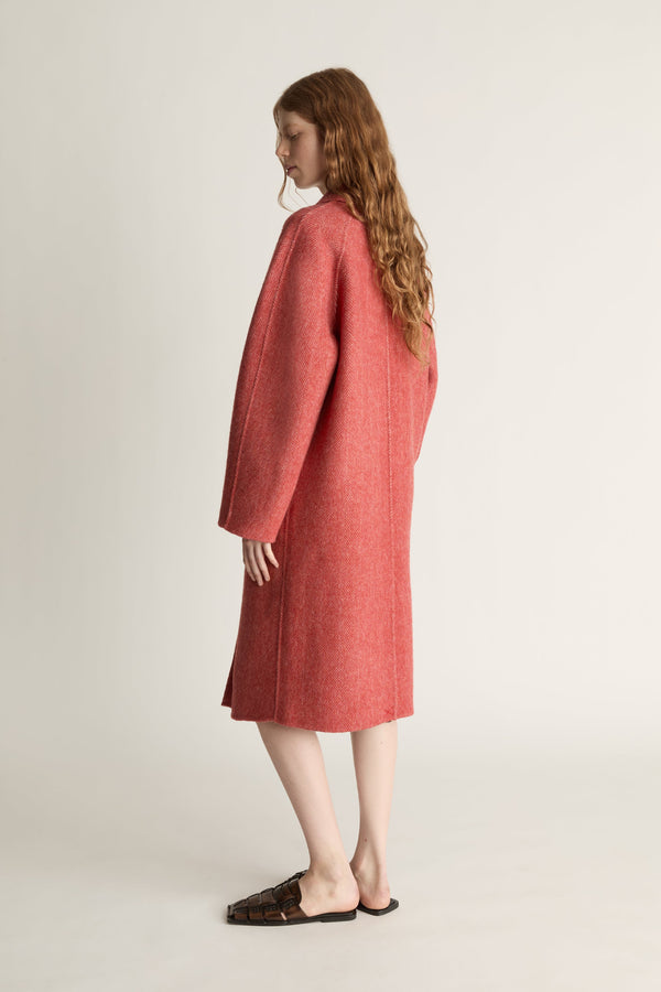 Person wearing a red coat on a plain background