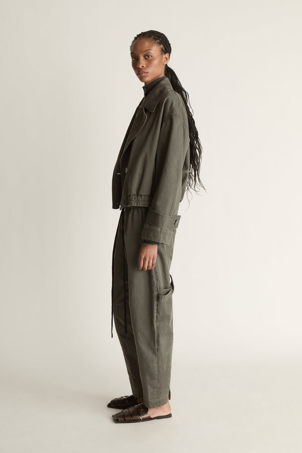 Person wearing a green coat and pants on a plain background
