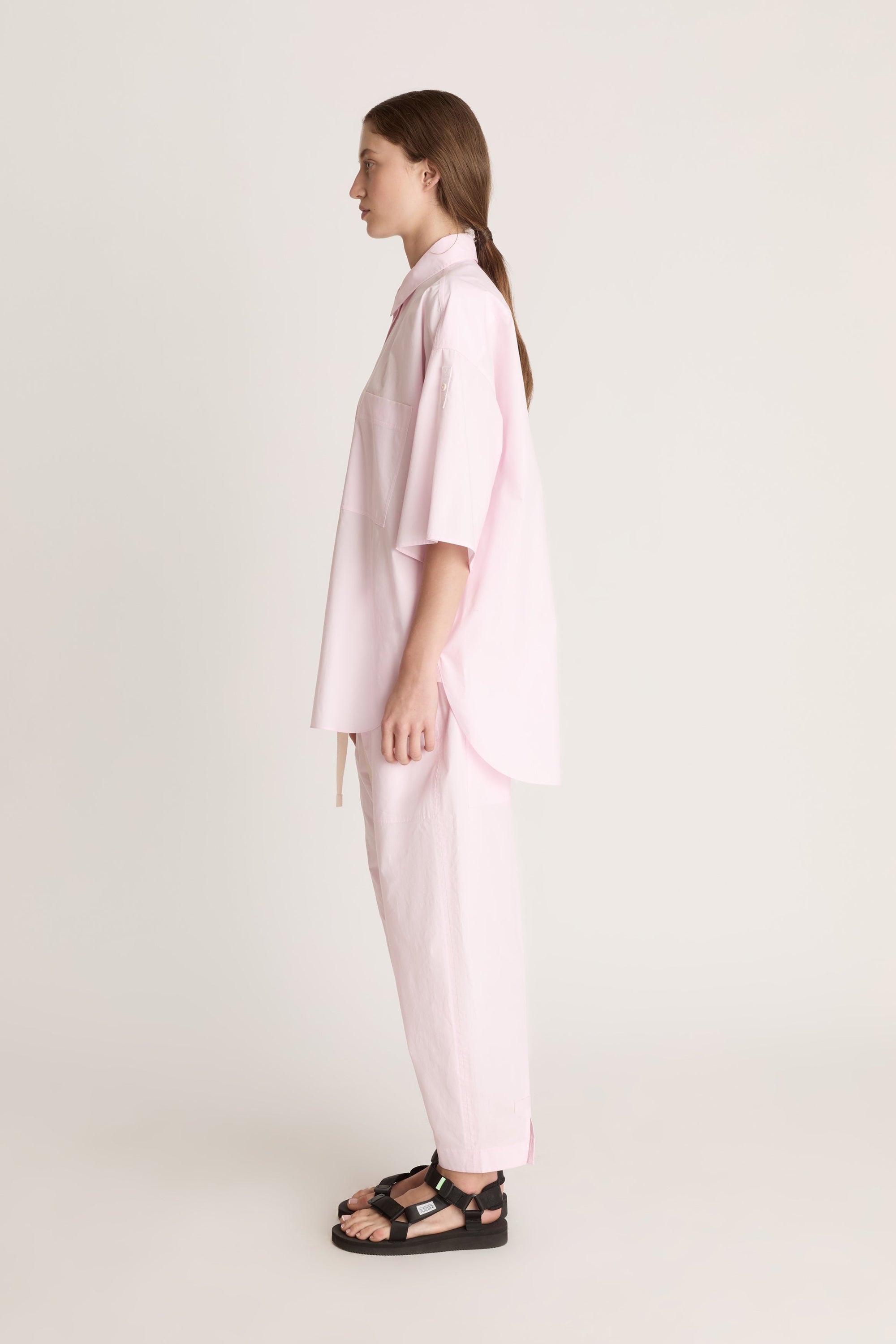 Person wearing a light pink shirt and pants on a white background