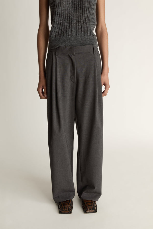 Woman wearing a sleeveless knitted top and wide-leg pants on a plain background