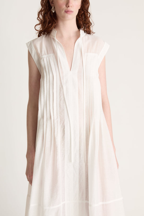 Woman wearing a long white dress with brown shoes on a white background