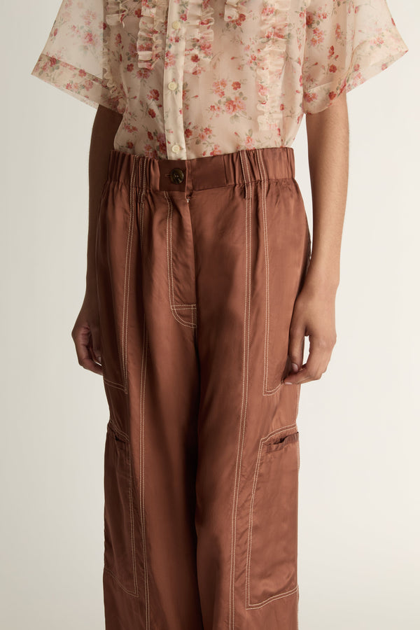 Person wearing a floral blouse and brown pants on a white background