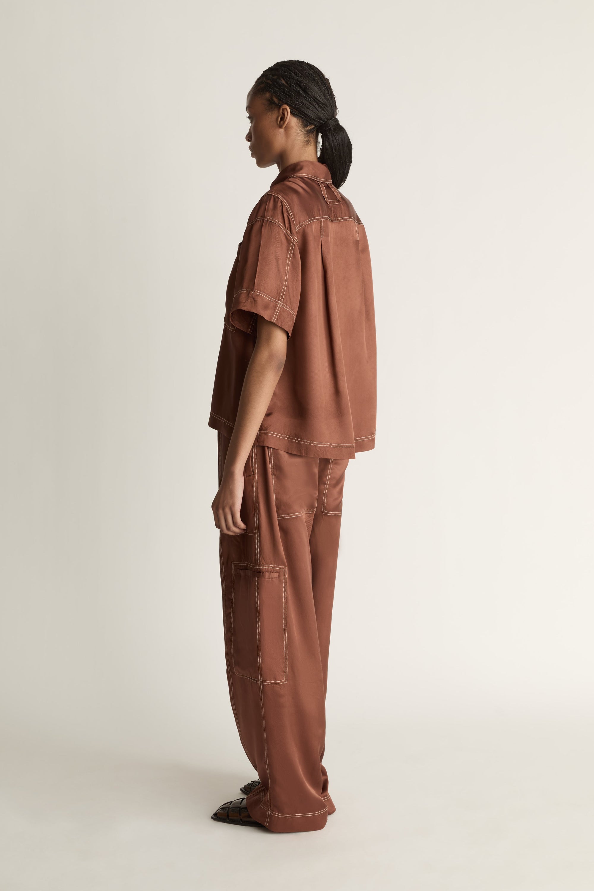 Person wearing a brown shirt and pants on a plain background