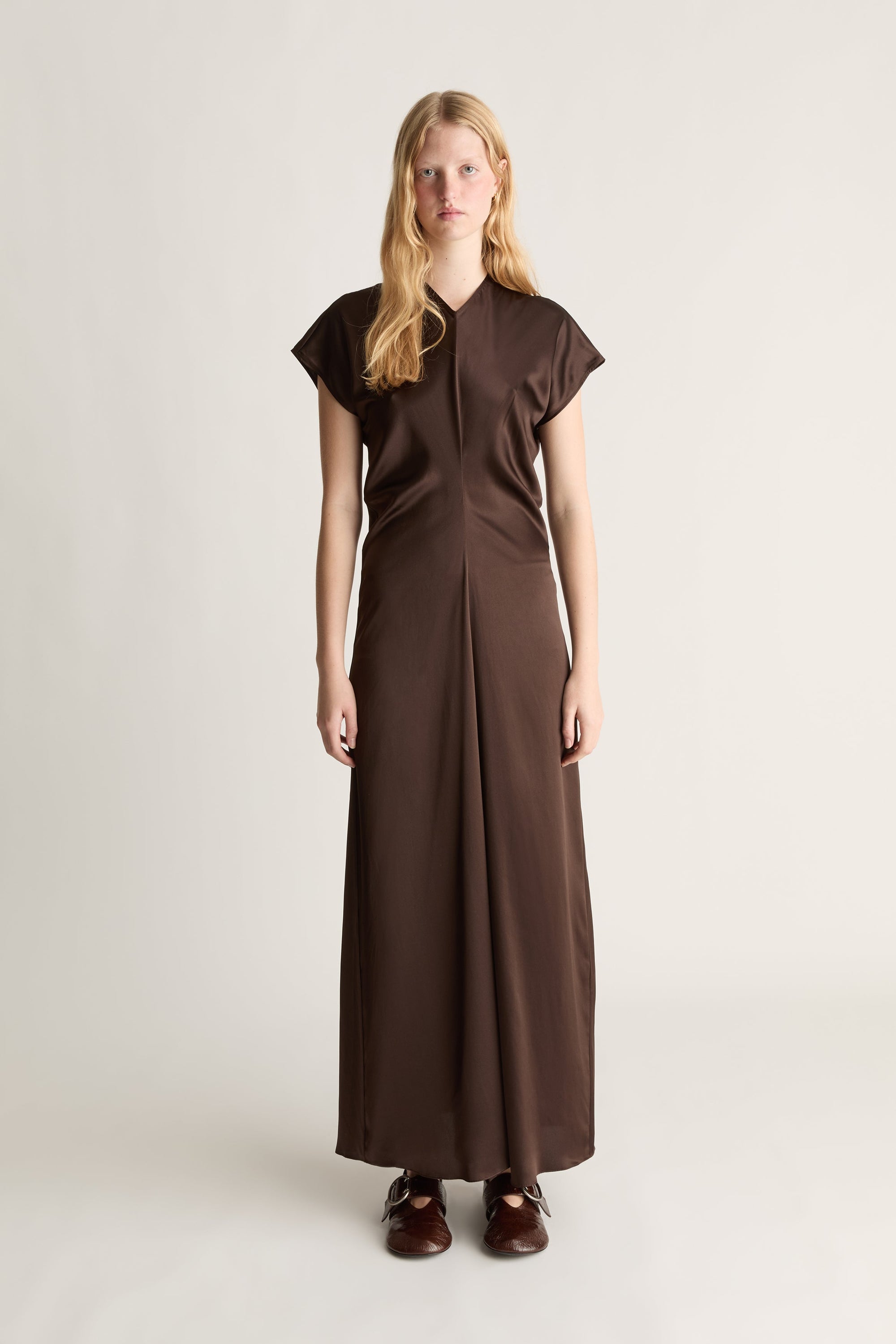 Front view of a woman wearing a brown dress on a white background