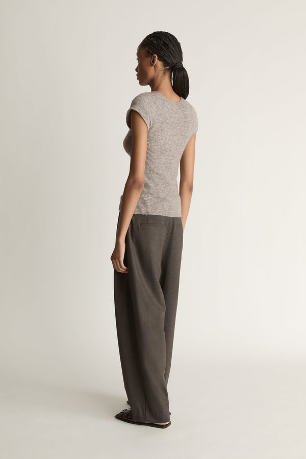 Woman wearing a gray sleeveless top and wide-leg pants on a white background